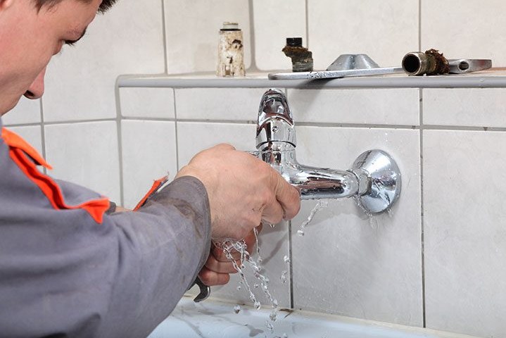 Gasfíter reparando una llave con filtración de agua